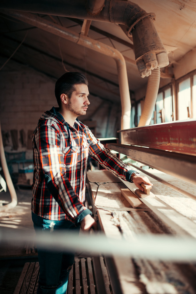 A maker hand-sanding a solid-wood component in the workshop